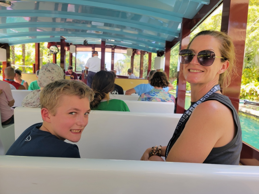 Woman and son sitting on a bench of a water taxi. Looking over shoulders smiling at the camera. 

